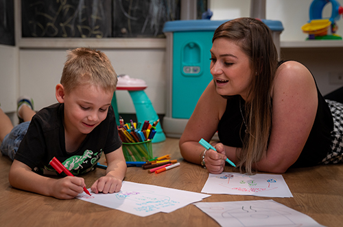 Child and child safety officer drawing at a desk